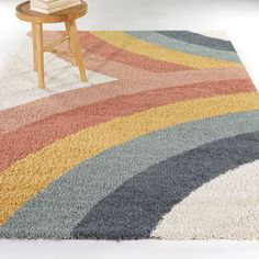 a multicolored rug with a wooden chair and table in the corner behind it