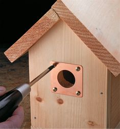 a person is working on a birdhouse with a screwdriver in their hand