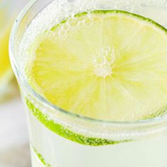 a glass filled with green liquid and a slice of lime