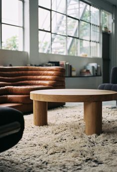 a round wooden table sitting on top of a shaggy rug