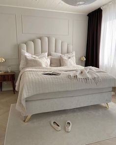 a bedroom with a white bed and two pairs of shoes on the floor