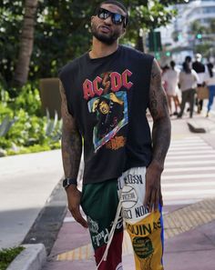 a man is walking down the street with his hand in his pocket and holding two bags