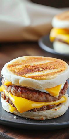 a breakfast sandwich with sausage, egg and cheese on a black plate sitting on a wooden table