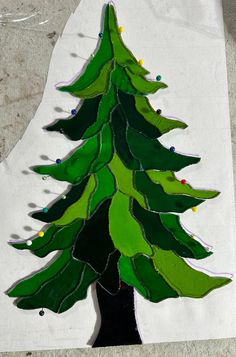 a christmas tree made out of stained glass on a piece of paper with string lights around it