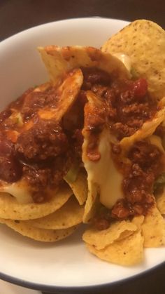 some tortilla chips with chili and cheese on top