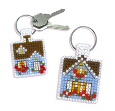 two key chains with houses on them and one has a house in the middle that is made out of beads