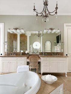 a large white bath tub sitting under a chandelier next to a bathroom sink