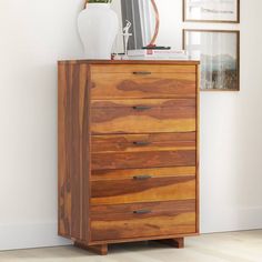 a wooden chest of drawers with a mirror on top and pictures hanging on the wall behind it