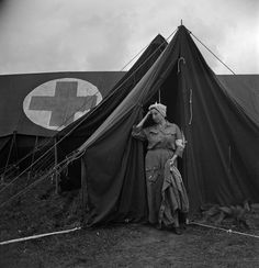 an old photo of a man standing in front of a tent with a cross on it