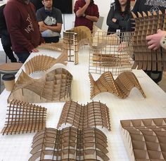 several people standing around a table with wooden models on it