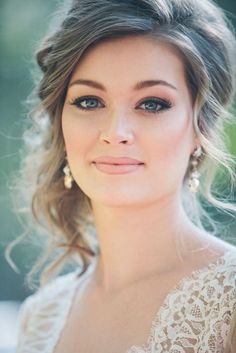 a beautiful woman with blue eyes and blonde hair wearing a white dress is smiling at the camera