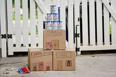 three cardboard boxes stacked on top of each other in front of a white picket fence