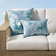 three blue and white pillows sitting on top of a couch next to a wooden railing