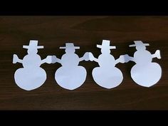 three snowmen cut out from paper on a table