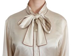 Discover the epitome of sophistication with this stunning Beige Silk Satin Blouse from Dolce & Gabbana. Boasting a QUEEN Embroidery on the left chest, this top exudes elegance and luxury. Featuring a classic collar with button closure and a scarf neck bow for an added touch of refinement, it’s the perfect piece to elevate any ensemble. Crafted in Italy with exquisite attention to detail, this blouse is a true testament to the brand’s commitment to high-end fashion. Material: 100% Silk Satin Colo Queen Embroidery, Satin Bluse, Beige Silk, Scarf Neck, Neck Bow, Satin Color, Dolce E Gabbana, Satin Blouse, Double Breasted Coat