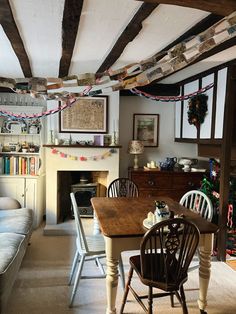 a living room filled with furniture and a fire place under a wooden beamed ceiling