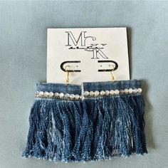 a pair of earrings with tassels hanging from it's ear hooks on top of a card