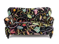 an upholstered couch with colorful flowers and leaves on black fabric, against a white background