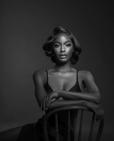 a black and white photo of a woman sitting in a chair with her arms crossed