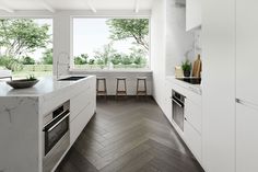 a modern kitchen with white cabinets and marble counter tops, along with wooden flooring