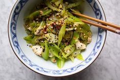 a blue and white bowl filled with food next to chopsticks