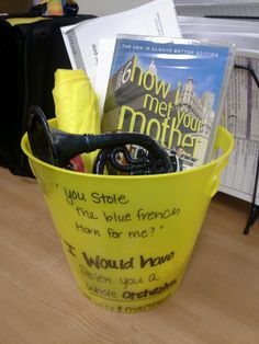 a yellow bucket filled with books on top of a wooden table