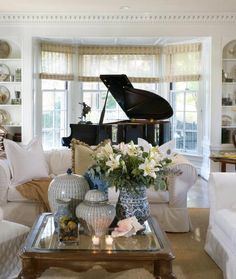 a living room filled with furniture and a grand piano in the window sill next to a coffee table