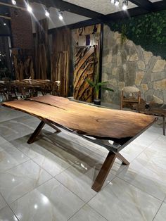 a large wooden table sitting on top of a tiled floor next to a stone wall