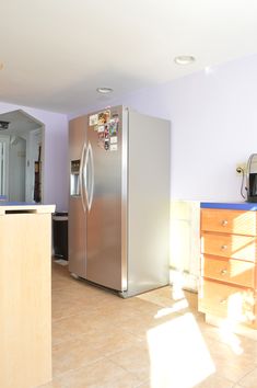 a kitchen that has a refrigerator in the middle of it, and cabinets on both sides