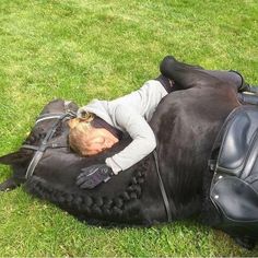 a woman laying on top of a black horse