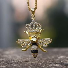 a gold necklace with a bee wearing a crown