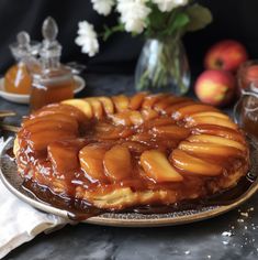 a cake on a plate with caramel toppings and flowers in the back ground