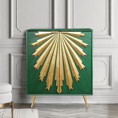 a green and gold art piece in front of a white wall