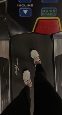 person standing on top of a machine with their feet in the air and wearing white sneakers