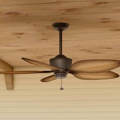 a ceiling fan mounted on the side of a wooden ceiling in front of a house