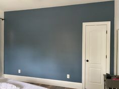 an empty bedroom with blue walls and white trim on the wall, along with a bed