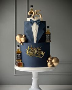 a blue and gold birthday cake with an elegant bow tie, bottle of booze