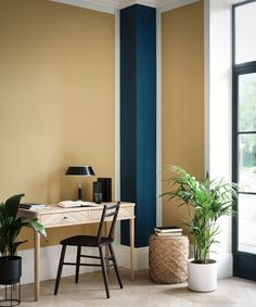 a room with a desk, chair and potted plant