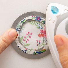 a person holding a remote control next to a flowered paper plate