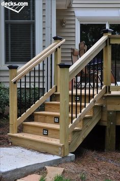 a wooden deck with stairs and railings in front of a house