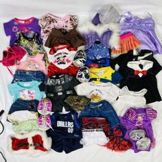 a pile of baby clothes sitting on top of a bed