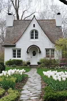 a white house with tulips in the front yard and walkway leading to it