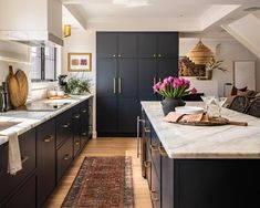 a kitchen with black cabinets and marble counter tops, along with a rug on the floor