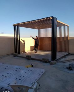 a woman standing in front of a metal structure on top of a cement floor next to a building