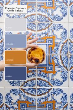 a hand holding a pie on top of a blue and white tile wall with orange accents