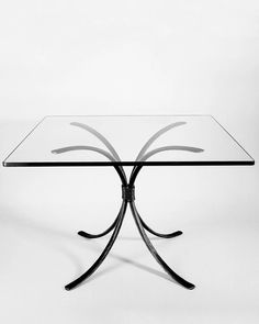 a glass table with black metal legs on a white background in the style of art deco