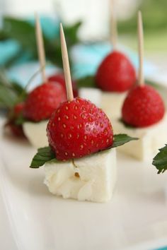 strawberries and cheese are arranged on toothpicks