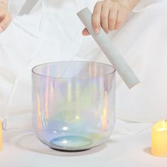 a woman is holding a piece of paper over a glass bowl with candles around it