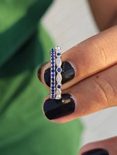 a woman's hand holding a ring with blue and white sapphires on it