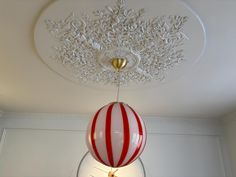 a red and white striped ball hanging from the ceiling in a room with chandelier